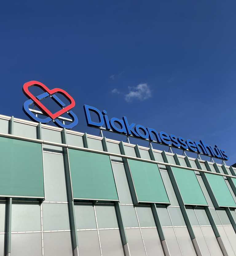 Verlichte dakreclame van het diakonessenhuis logo
